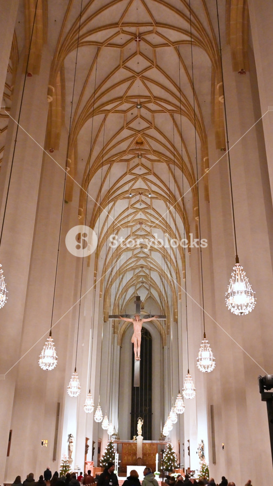 Munich, germany, december 27, 2025. Impressive interior view of historic cathedral frauenkirche with gothic vaulted ceilings, ornate chandeliers, and a large crucifix hanging above the nave
