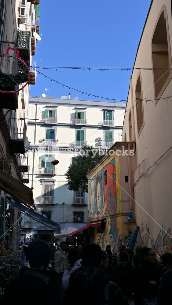 Naples, Italy, December 29, 2024. Vertical footage inside an alley in the historic center, where the fish market is held. People walking along the vendors' stalls. City life.
