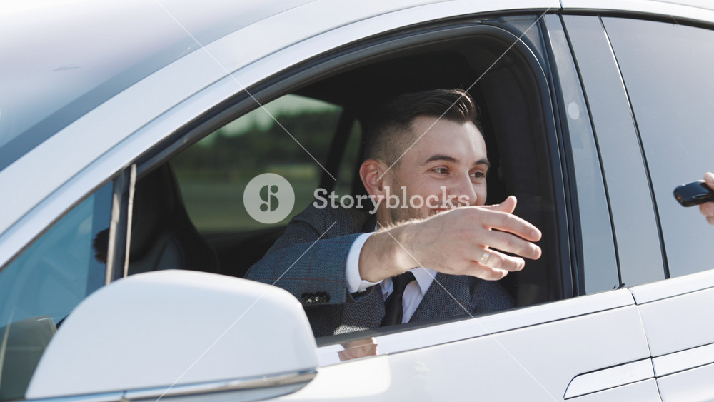 Young happy man receiving car keys to her new automobile. Car salesman finishing up dealing car. Businessman giving car key contract buying