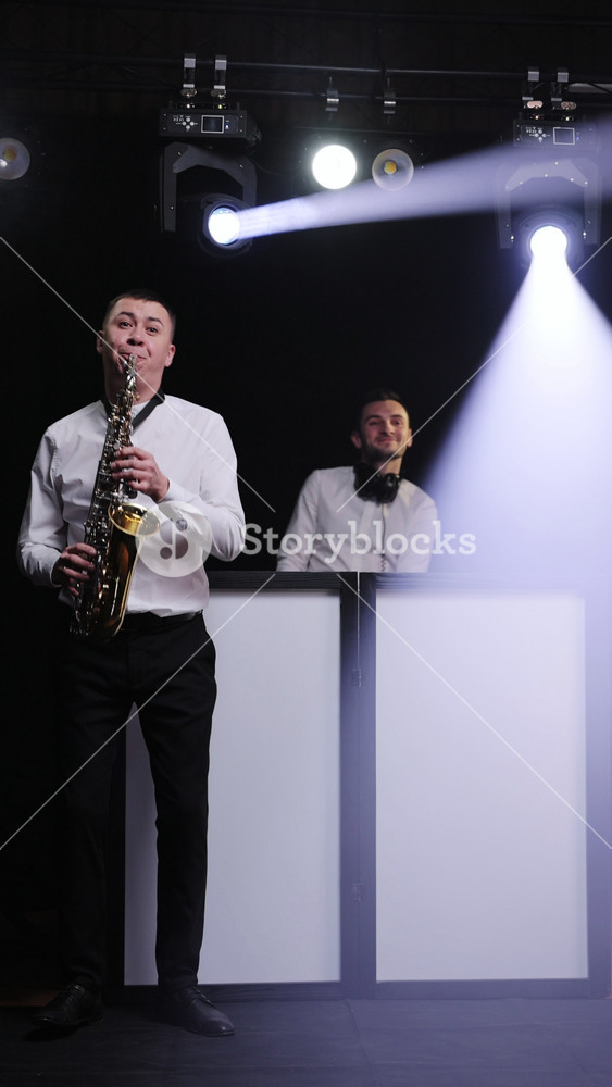 Vertical Video of DJ Playing Music in Nightclub. Saxophonist man with saxophone standing in nightclub playing sax, dancing, performing on