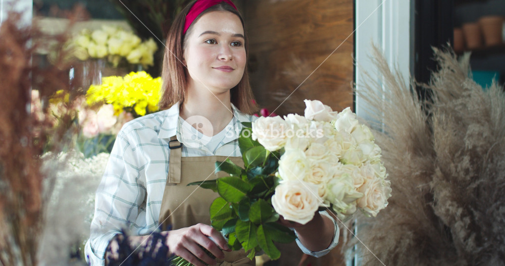 Charming female seller receiving money from customer and giving him order in flower store. Young Caucasian man client giving payment and