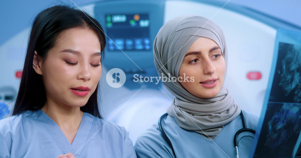 Doctor in hijab looking at MRI image. Muslim doctor consulting with intern. Doctor exploring image of MRI examination. Clinic of magnetic