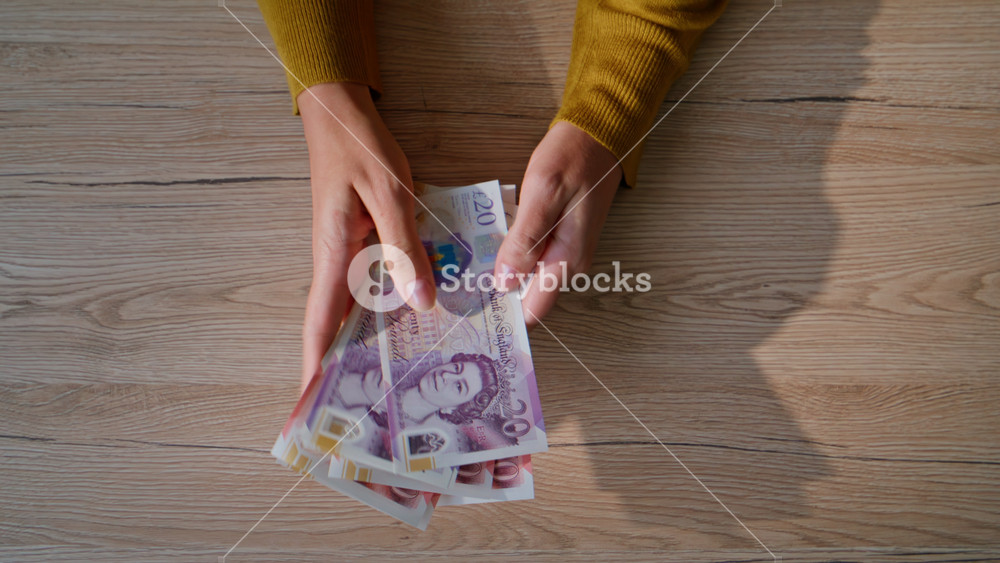 Hands counting British pounds at workplace closeup top view. Unrecognizable woman holding money bills at office wooden desk. Businesswoman