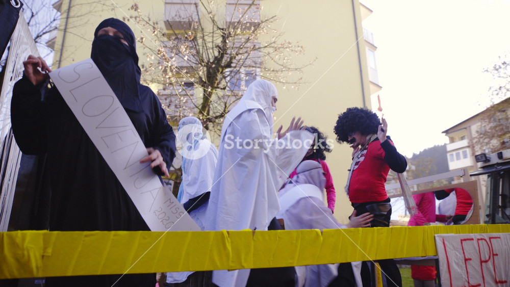 LITIJA, SLOVENIA 2016: Muslim girls carnival parade with moving stage 4K. Panning shot of stage driving down the road with Muslim girls masked under black and white dresses. Carnival parade in Litija, Slovenia.