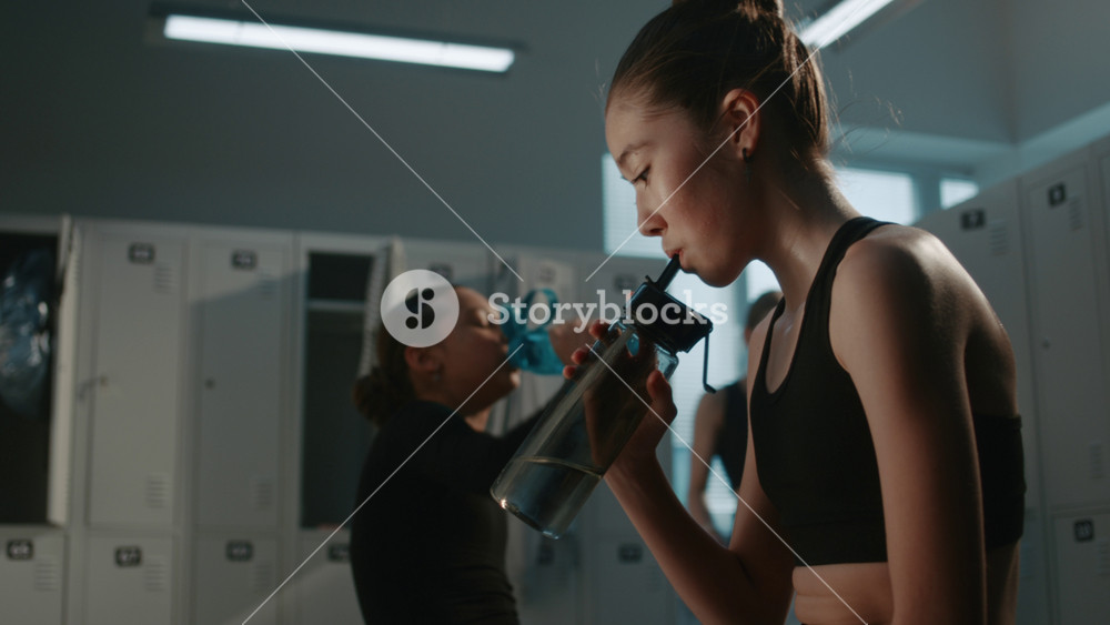 Sweaty Teenage in Locker Room after Demanding Workout Session. Girls Drink Water and Complain to Each Other about Strict Coach, Hard