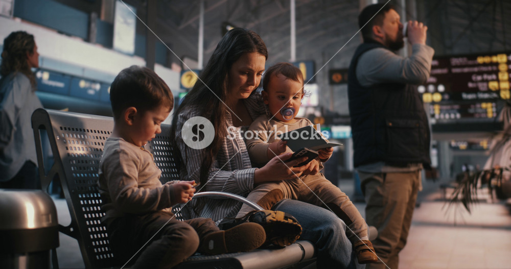 Young Mother Sits in Departure Lounge, Holding Baby and Showing Travel Documents to Older Son. Family Travel, Parenting Challenges During