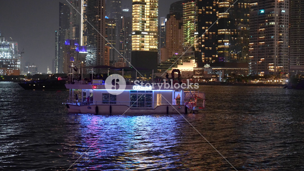 A striking night scene from a luxury yacht shows the illuminated city skyscrapers and other ships navigating the busy harbor, symbolizing exclusive high-end travel amidst vibrant urban nightlife.