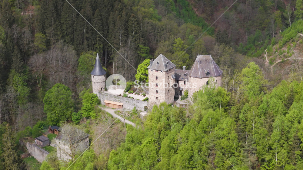 reinhardstein castle belgium rises dense woodland rugged stone towers slate roofs fortified walls nestled into green hillside from setting medieval architecture historic fortress