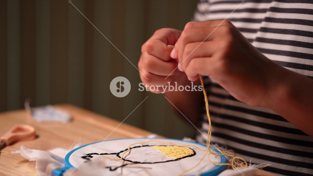 Close-up of a girl's hand embroidering a circle of embroidery with a frame. Girl person handmade craft sewing pattern on canvas.