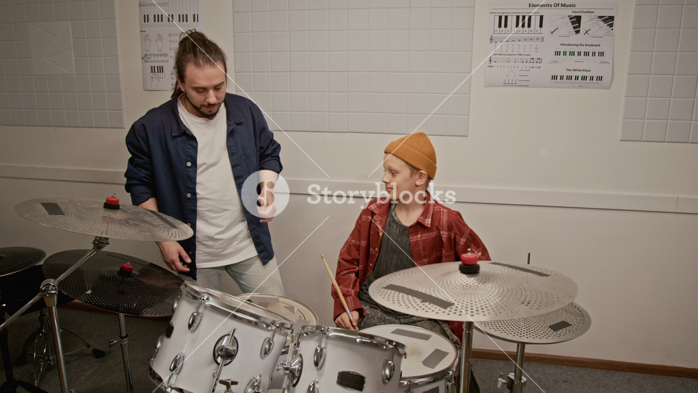Young male instructor teaching teenage boy playing drums during music lesson. Footage for promoting music schools and youth extracurricular activities