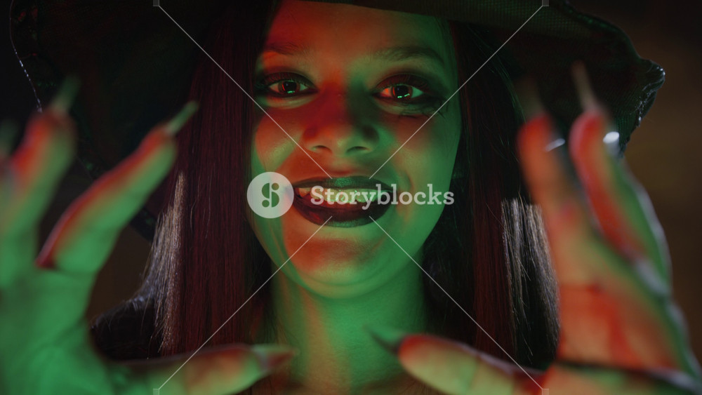 Portrait of teenage girl dressed as witch gesturing with clawed hands towards camera in slow motion. Clip is ideal for Halloween marketing campaigns or themed event promotions