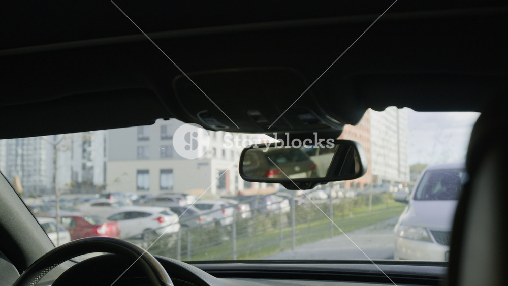Reflection in rear view mirror of middle aged male personal driver sitting in front seat of business car at parking lot, providing premium service for important clients