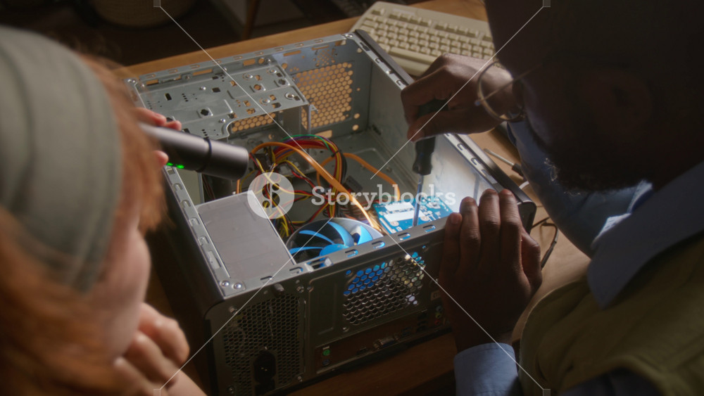 Over the shoulder shot of African American man and Caucasian woman repairing desktop computer tower, unscrewing graphics card. Clip is perfect for IT support services and tech education promos