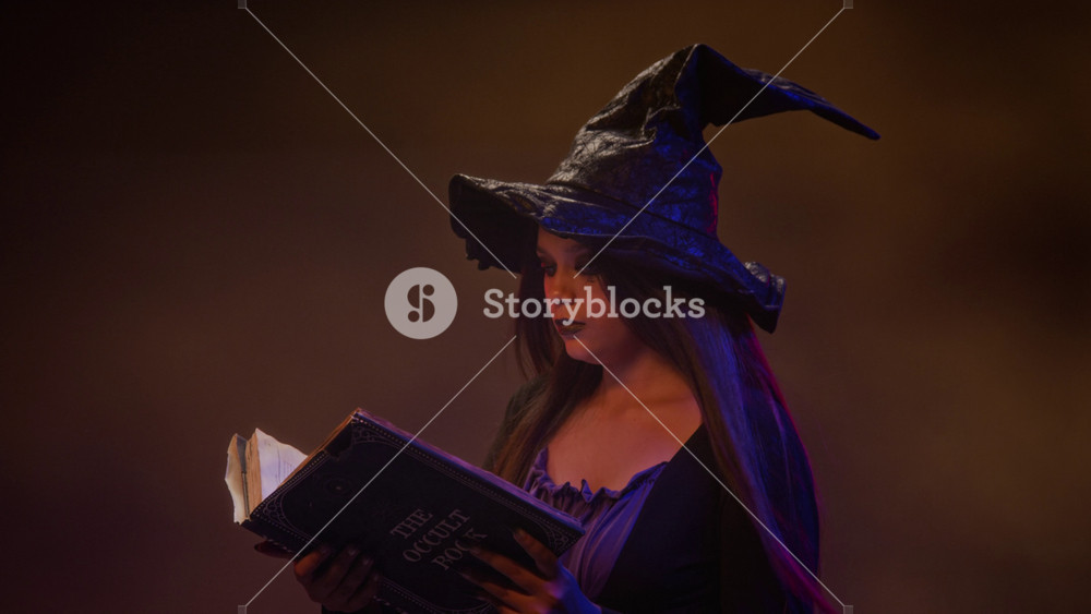 Girl dressed as witch opening and reading occult book. Clip is perfect for Halloween retail advertisements, holiday marketing campaigns, and fantasy themed content
