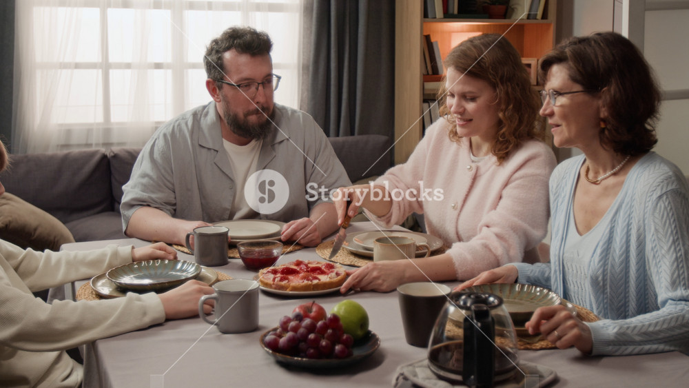 Multigenerational Caucasian family sitting at dining table with woman slicing homemade pie. Clip for food delivery ads and family lifestyle marketing