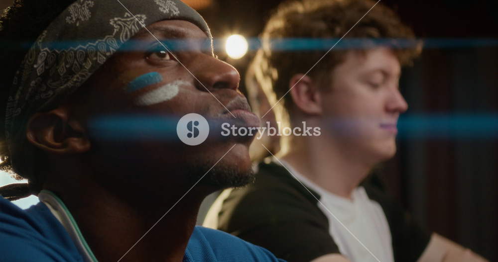 Close up shot of upset African American man wearing fan make up and uniform watching his football team lose at bar