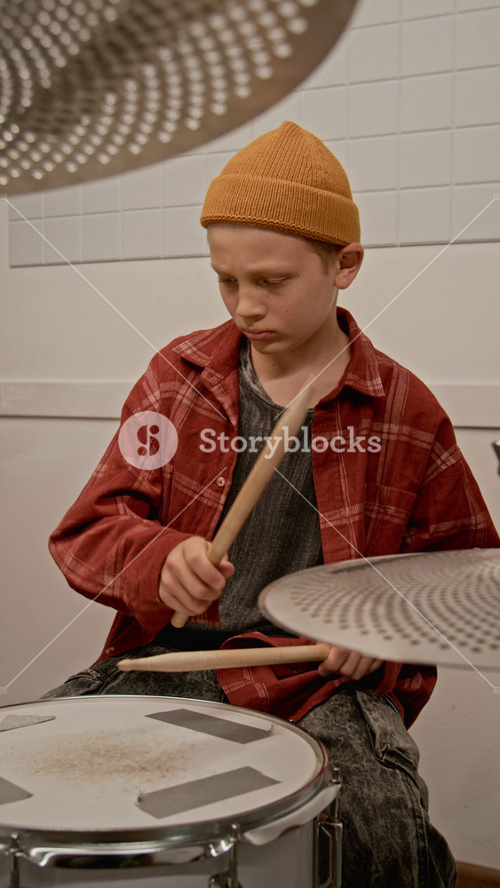 Vertical video of Caucasian teenage boy practicing drums with drumsticks in music studio. Clip for marketing youth music schools and creative extracurricular activities