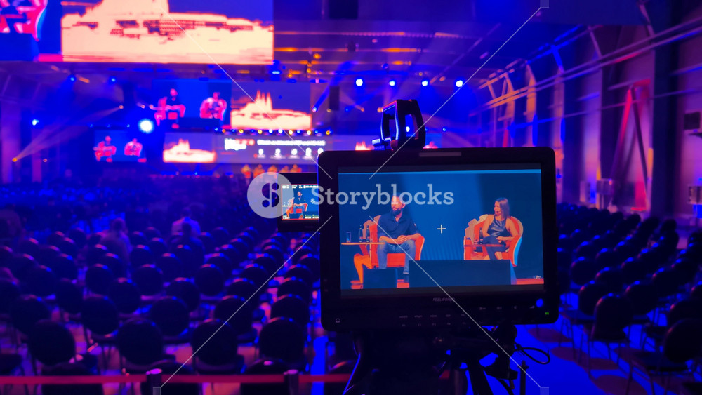 PRAGUE, CZECH REPUBLIC - JUNE 14, 2024: A camera display shows speakers on the stage of a Bitcoin conference - closeup - the chairs and the stage in the blurry background