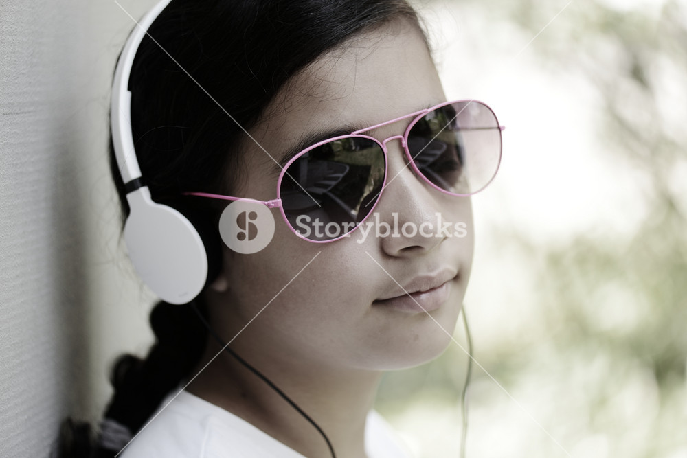 Teenage girl with sunglasses enjoying music on headphones
