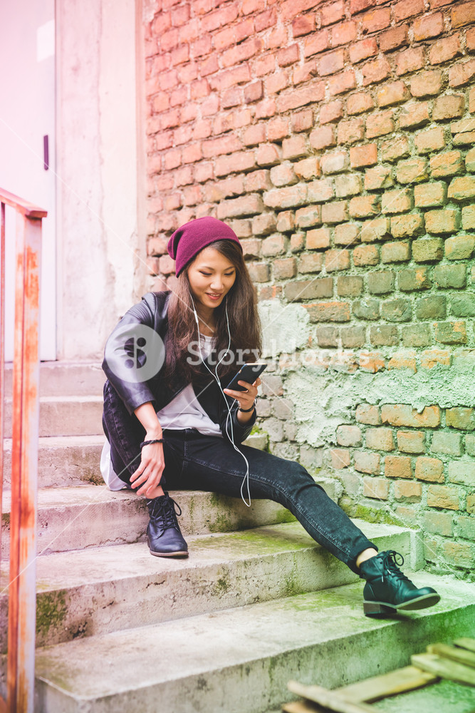 Beautiful young woman enjoying music outdoors with earphones and smartphone - music, technology, leisure concept
