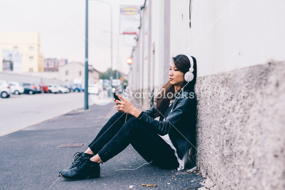 Beautiful young woman enjoying music outdoors with headphones and smartphone - music, technology, leisure concept