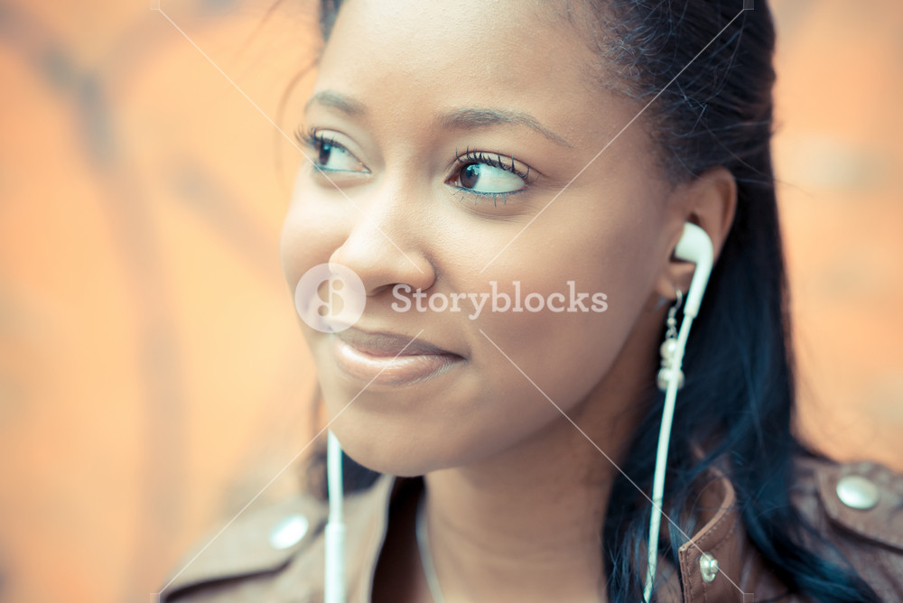 Stylish young woman enjoying music with earphones in the city