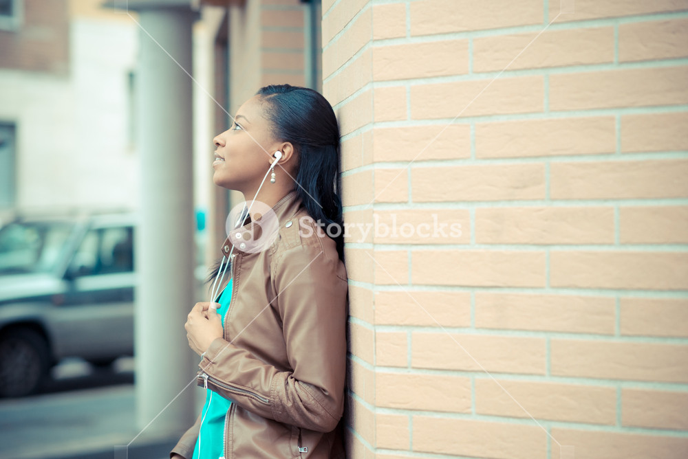 Stylish young woman enjoying music with earphones in the city
