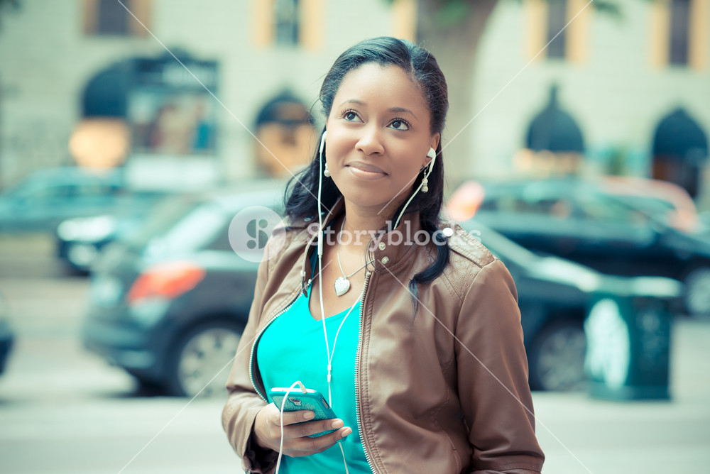 Stylish young woman enjoying music with earphones in the city