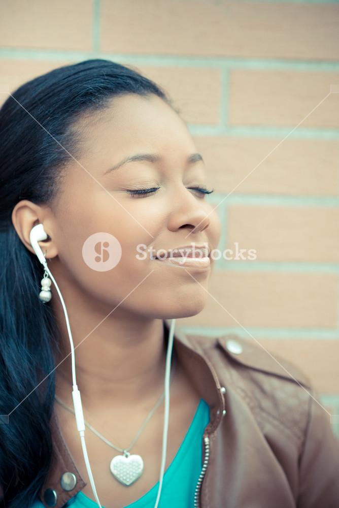 Stylish young woman enjoying music with earphones in the city
