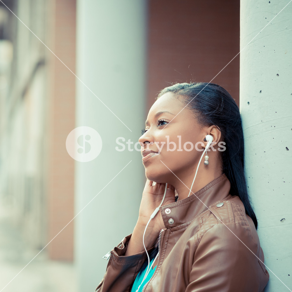 Stylish young woman enjoying music with earphones in the city