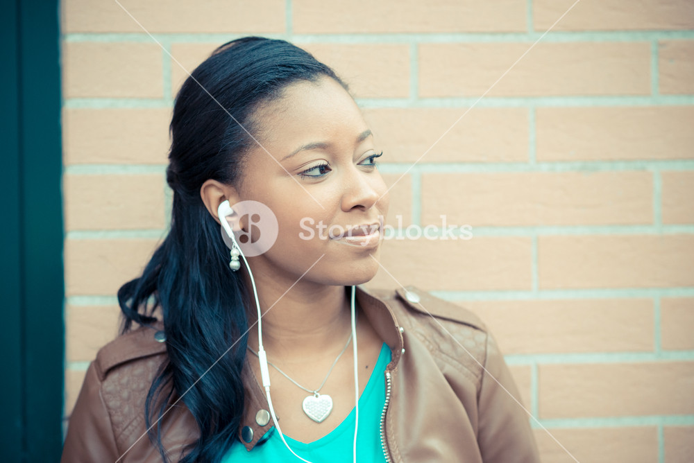 Stylish young woman enjoying music with earphones in the city