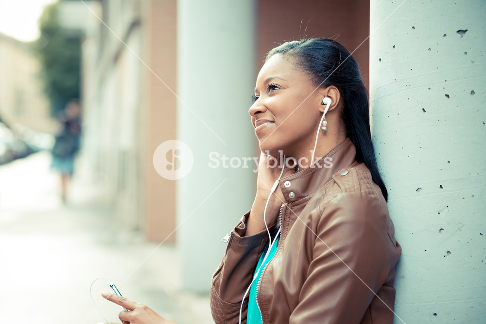 Stylish young woman enjoying music with earphones in the city