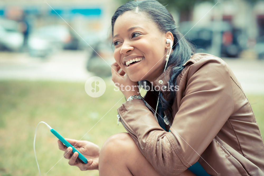 Stylish young woman enjoying music with earphones in the city