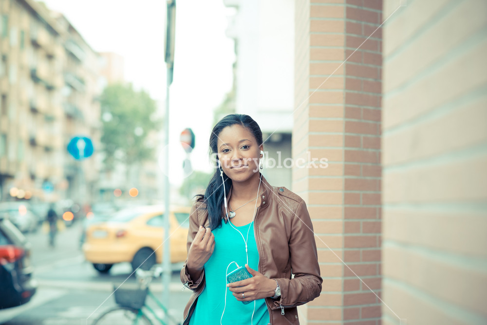 Stylish young woman enjoying music with earphones in the city