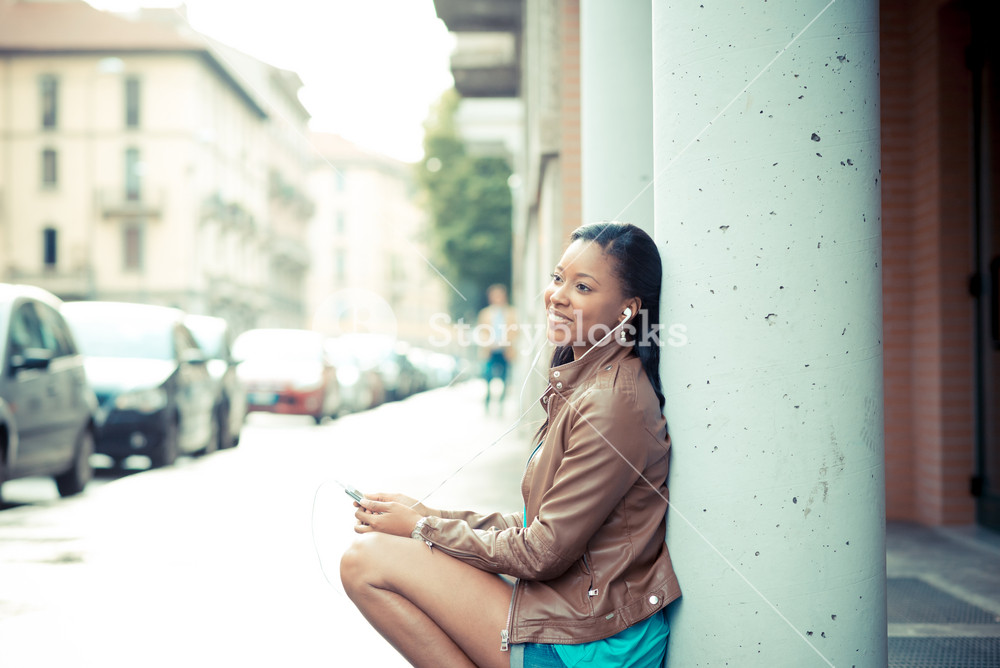 Stylish young woman enjoying music with earphones in the city
