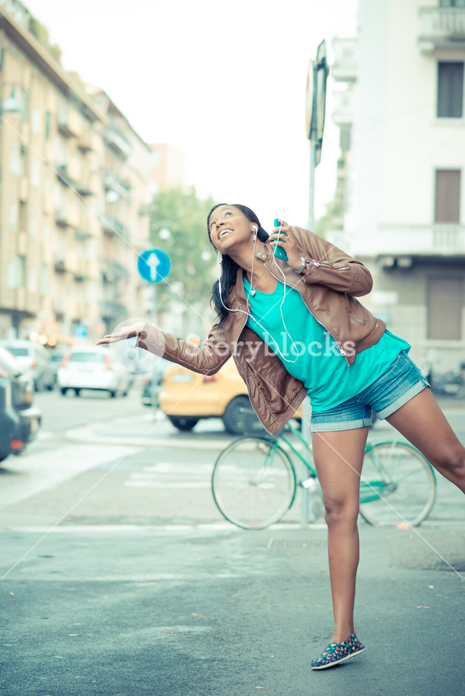 Stylish young woman enjoying music with earphones in the city