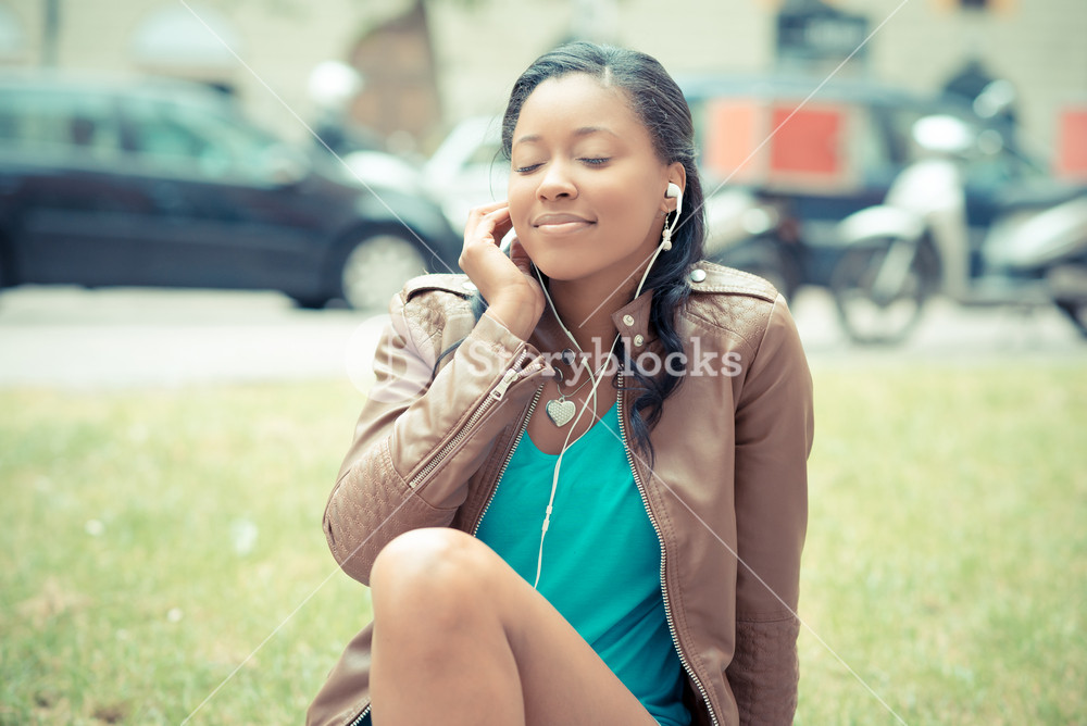 Stylish young woman enjoying music with earphones in the city