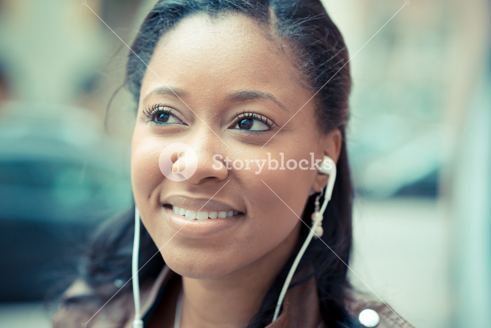 Stylish young woman enjoying music with earphones in the city