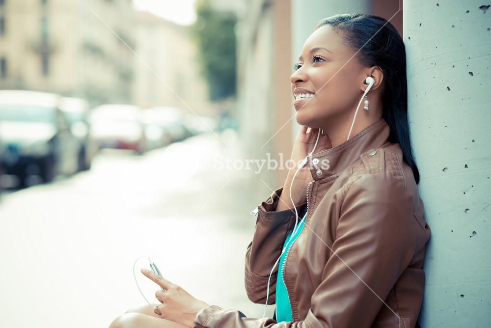 Stylish young woman enjoying music with earphones in the city