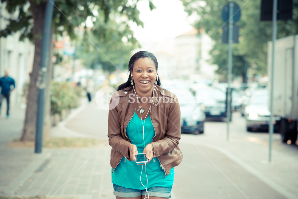 Stylish young woman enjoying music with earphones in the city