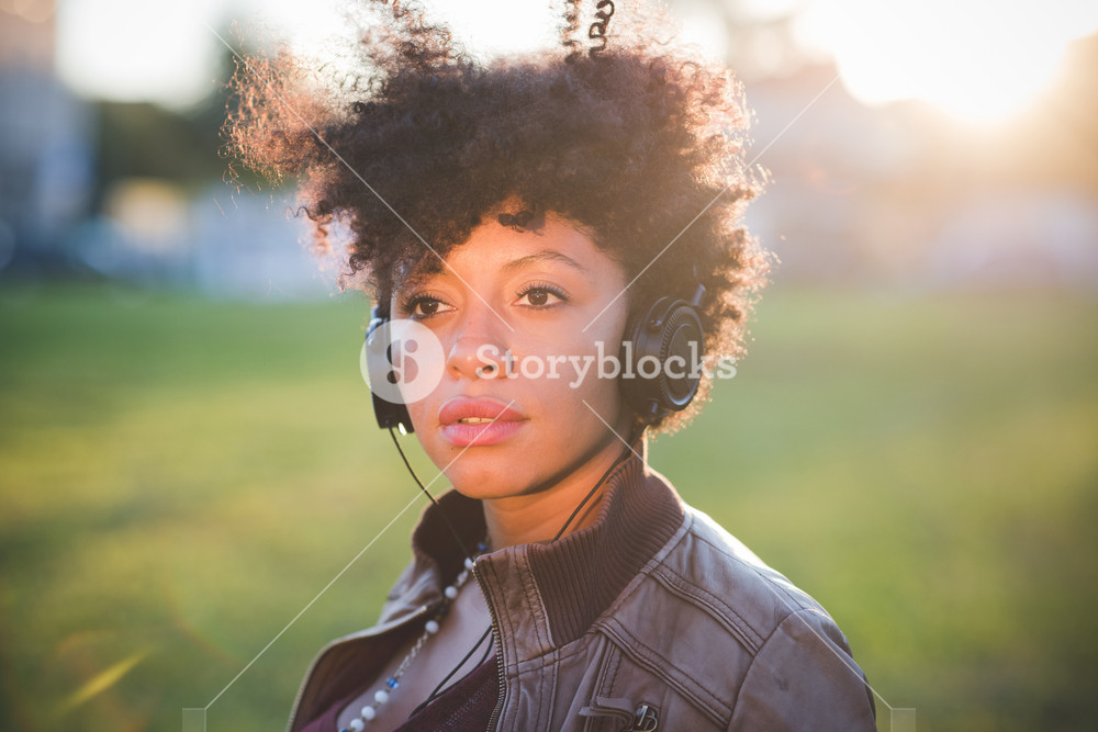 Stylish woman with curly hair enjoying music in town