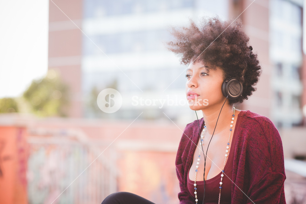 Stylish woman with curly hair enjoying music in town