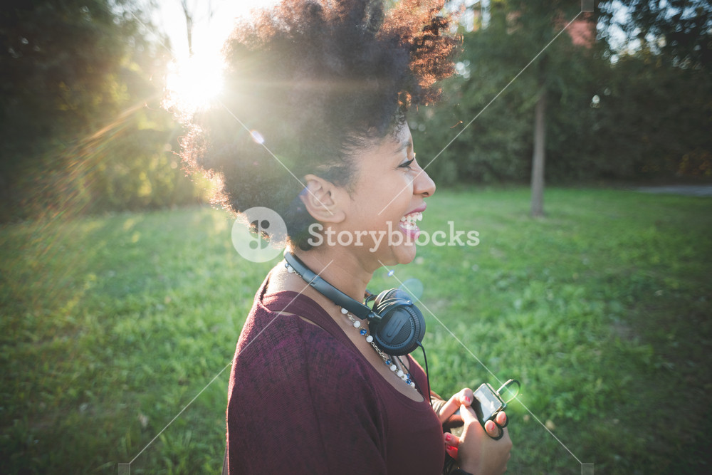Stylish woman with curly hair enjoying music in town