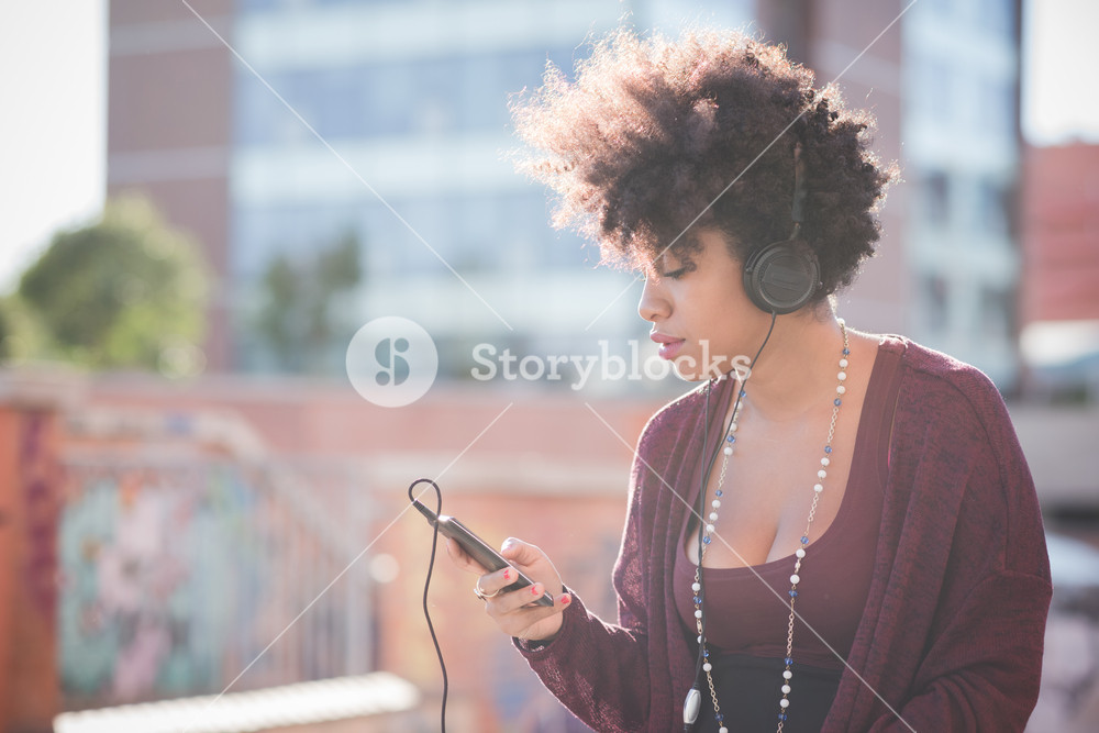 Stylish woman with curly hair enjoying music in town