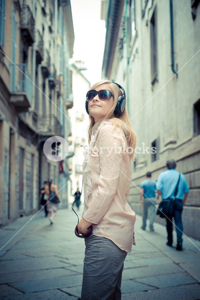 Stylish woman enjoying music in the city