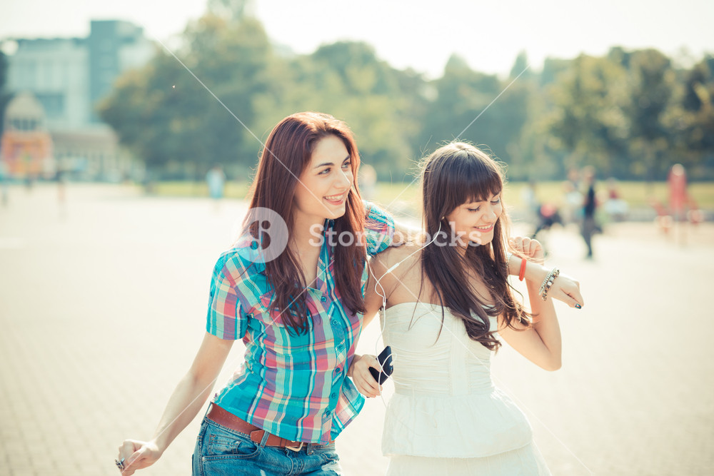 Stylish young women enjoying music and dancing together in the city