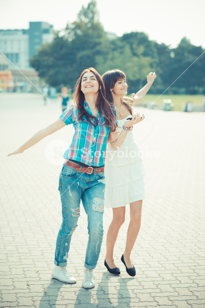 Stylish young women enjoying music and dancing together in the city