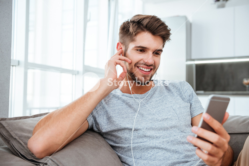 Portrait of a young man enjoying music and conversation on a sofa
