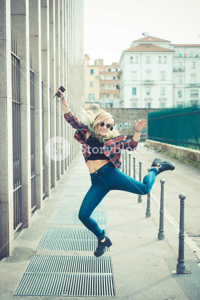 Young woman joyfully dancing and listening to music in the city