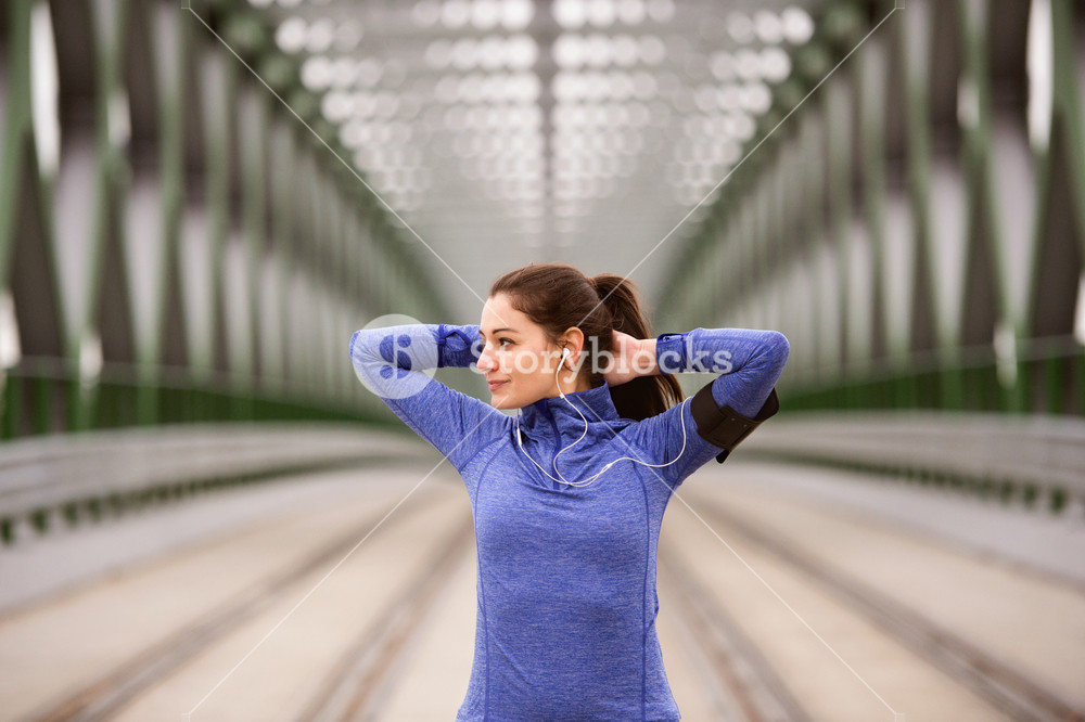 Young runner warming up and stretching on green steel bridge in the city.